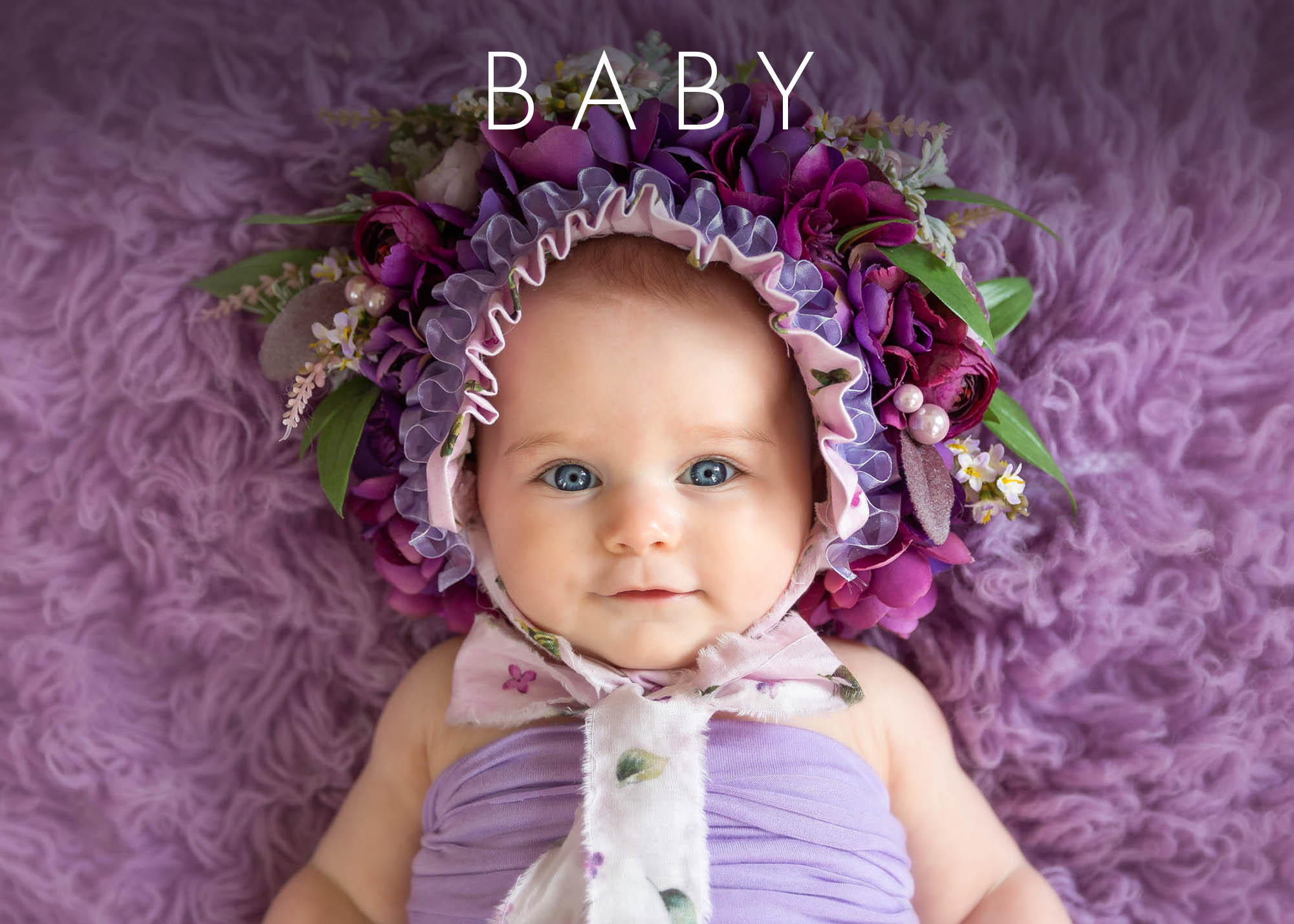 Newborn Photographer, a baby girl wears a decorative flower hat on a fluffy purple blanket